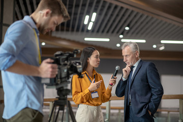 Young female reporter having interview with famous businessman - obrazy, fototapety, plakaty