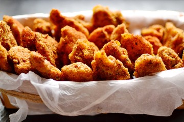 Chicken nuggets on a dark background. Grilled fish and meat in batter. Fish sticks. Meat sticks. Nuggets with tomato and parsley in a basket. Place for your text.