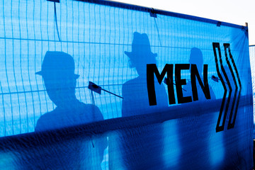 Silhouettes of four men using the toilets at a music festival.