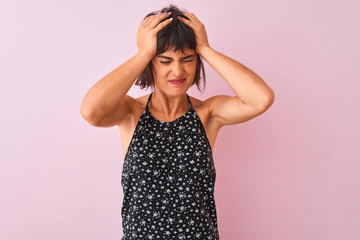 Young beautiful woman wearing black floral dress standing over isolated pink background suffering from headache desperate and stressed because pain and migraine. Hands on head.