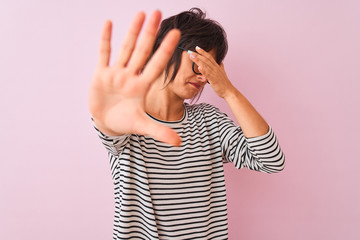 Young beautiful woman wearing striped t-shirt and glasses over isolated pink background covering eyes with hands and doing stop gesture with sad and fear expression. Embarrassed and negative concept.