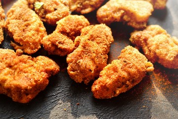 Fried crispy chicken nuggets on a dark background. Tasty fried chicken meat isolated. Place for text.
