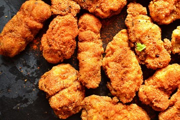 Fried crispy chicken nuggets on a dark background. Tasty fried chicken meat isolated. Place for text.