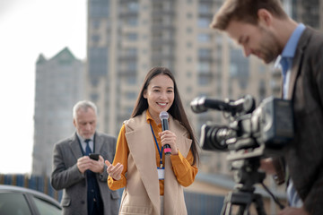 Young cute female reporter talking to a videocamera