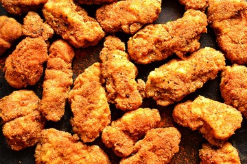 Fried crispy chicken nuggets on a dark background. Tasty fried chicken meat isolated. Place for text.