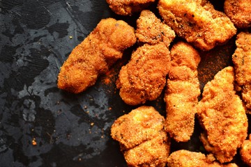 Fried crispy chicken nuggets on a dark background. Tasty fried chicken meat isolated. Place for...