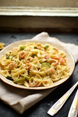 Italian pasta in a creamy sauce with shrimp on a plate, top view. Pasta in the form of bows on a dark table background. 