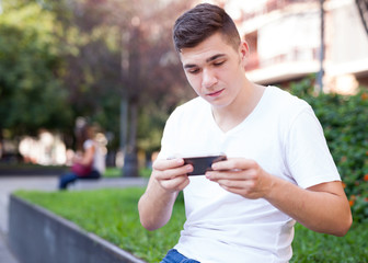 Fototapeta na wymiar Guy texting on his smartphone in park
