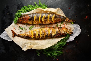 Cooked fish on a dark background. Oven baked mackerel with lemon and dill.