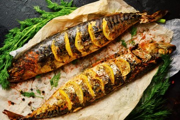 Cooked fish on a dark background. Oven baked mackerel with lemon and dill.