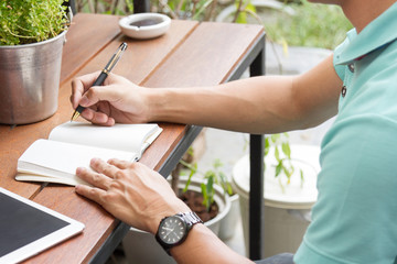 man writing on notebook with pen