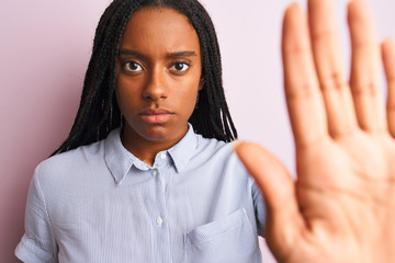 Young african american woman wearing striped shirt standing over isolated pink background with open...