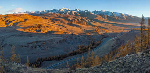 View of the mountain valley, evening light. Autumn nature, snow on the peaks.