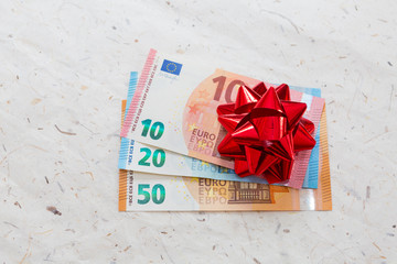 rote gebundene Geschenkschleife auf Euroscheinen, Geldgeschenk Konzept