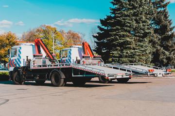 Two new tow trucks parked near the road in the city. Cranes on truck to towing cars. Urban....