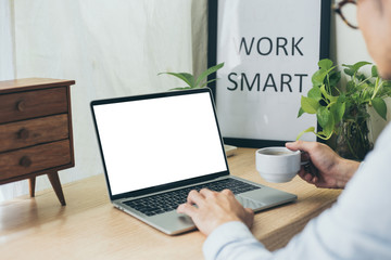 mockup image blank screen computer with blank white background for advertising text,hand man using laptop contact business search information on desk at home office.marketing and creative design