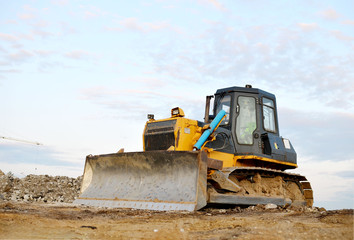 Obraz na płótnie Canvas Track-type bulldozer, earth-moving equipment. Land clearing, grading, pool excavation, utility trenching, utility trenching and foundation digging during of large construction jobs.