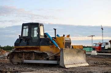 Obraz na płótnie Canvas Track-type bulldozer on construction site. Land clearing, grading, pool excavation, utility trenching and foundation digging during of large construction jobs. Earth-moving equipment