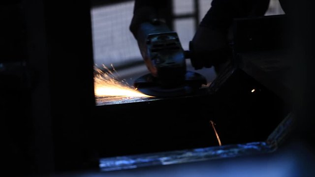 The man works circular saw, Flies of spark from hot metal, The man's hard work, Man Chlef and smooth surface, Man worked over the steel, close-up of hand and electric saws metal