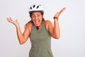 Middle age mature cyclist woman wearing safety helmet over isolated background celebrating crazy and amazed for success with arms raised and open eyes screaming excited. Winner concept