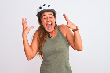 Middle age mature cyclist woman wearing safety helmet over isolated background celebrating mad and crazy for success with arms raised and closed eyes screaming excited. Winner concept