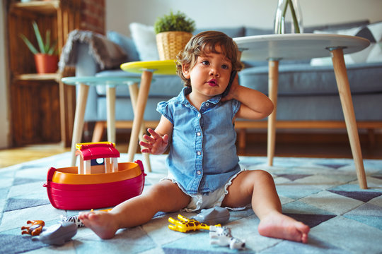 Beautiful toddler child girl sitting on the carpet playing with smartphone