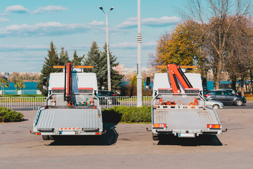 Two tow trucks with equipped hydraulic manipulator. Urban. Back view. Cranes. City. Road