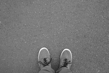 feet in canvas shoes standing on street - foot selfie from personal perspective point of view - asphalt background with copy space