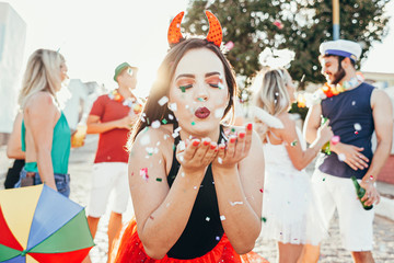 Brazilian Carnival. Young woman in costume enjoying the carnival party blowing confetti