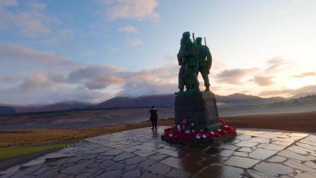 A woman taking photographs of the scenery from the commando memorial in Scotland during sunset