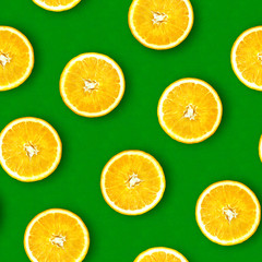Seamless pattern of oranges. Bright green background. Juicy orange in a cut. Citrus fruit.