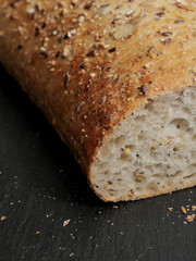 Fresh sourdough bread on a black slate plate on wooden table. Close up.