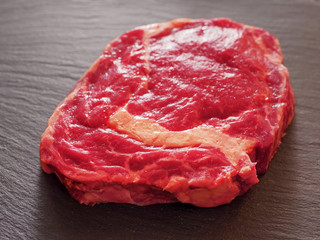 Fresh and juicy uncooked rib eye steak, premium cut of beef. On a stone surface, selective focus.