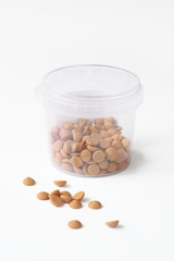 Belgian Caramel Chocolate in a transparent bucket, on white background.