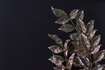 Closeup of golden leaves on dark background. Christmas banner. Copy space.