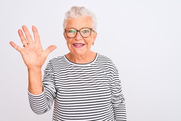 Senior grey-haired woman wearing striped navy t-shirt glasses over isolated white background showing and pointing up with fingers number five while smiling confident and happy.