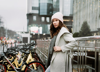 Young brunette woman walking around the city. She's wearing a gray coat and blue jeans