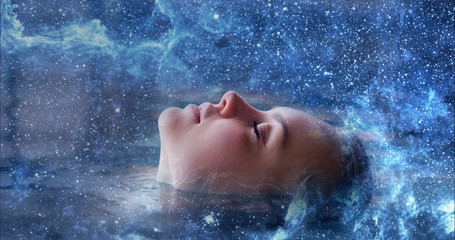 Close up of an young woman is enjoying and having relax immersed in an abstract milky way. Concept...