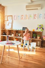 Beautiful blond toddler girl playing with loupe at kindergarten