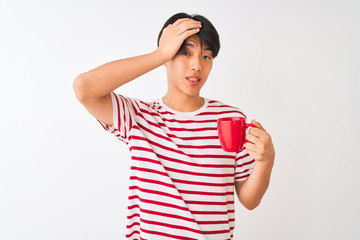 Young chinese man drinking a cup of coffee standing over isolated white background stressed with hand on head, shocked with shame and surprise face, angry and frustrated. Fear and upset for mistake.