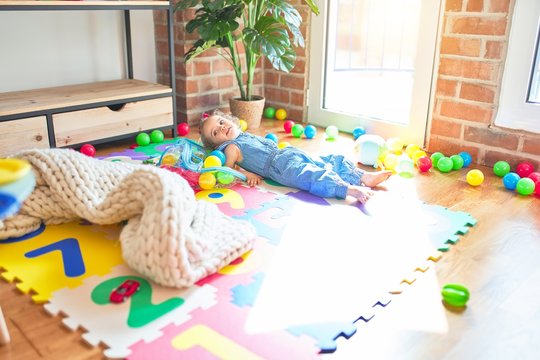 Beautiful caucasian infant playing with toys at colorful playroom. Happy and playful wth colorful balls at kindergarten.