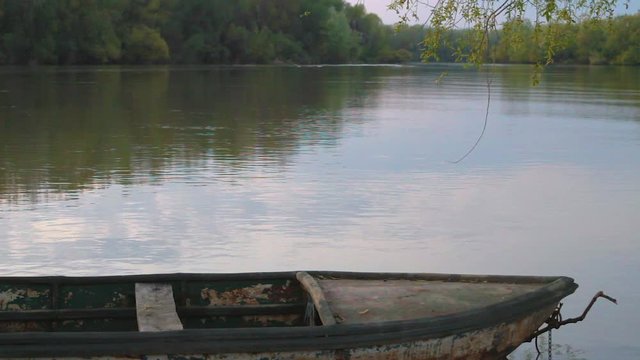 Picturesque wide shot of the Hungarian lake Tisza. Old rusty Boat floating in the foreground and moving bigger as the waves approaching.