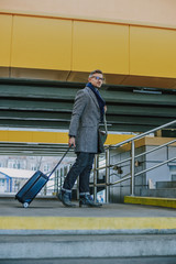 Handsome young man carrying travel suitcase and smiling
