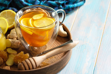 Cup of hot tea with lemon, ginger, honeycomb and honey on a wooden table. Copy space.