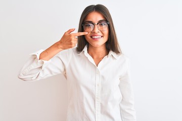 Young beautiful businesswoman wearing glasses standing over isolated white background Pointing with hand finger to face and nose, smiling cheerful. Beauty concept