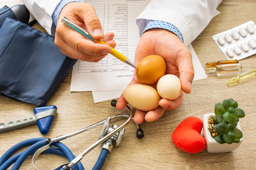Doctor nutritionist during consultation held in his hand and shows patient raw eggs. Counseling and...
