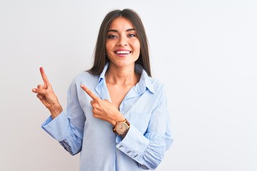 Young beautiful woman wearing blue elegant shirt standing over isolated white background smiling and looking at the camera pointing with two hands and fingers to the side.