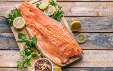 Close-up fresh appetizing salmon steak. Spices, lemon, fresh parsley and ice. Rustic background. Organic food. Top view