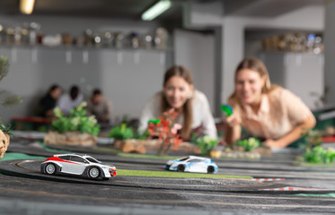 Emotional portrait of two women holding remote control and playing slot car racing