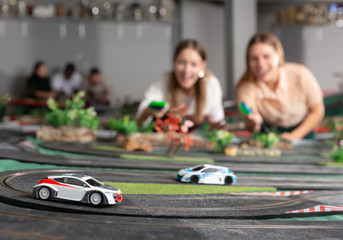Emotional portrait of two women holding remote control and playing slot car racing